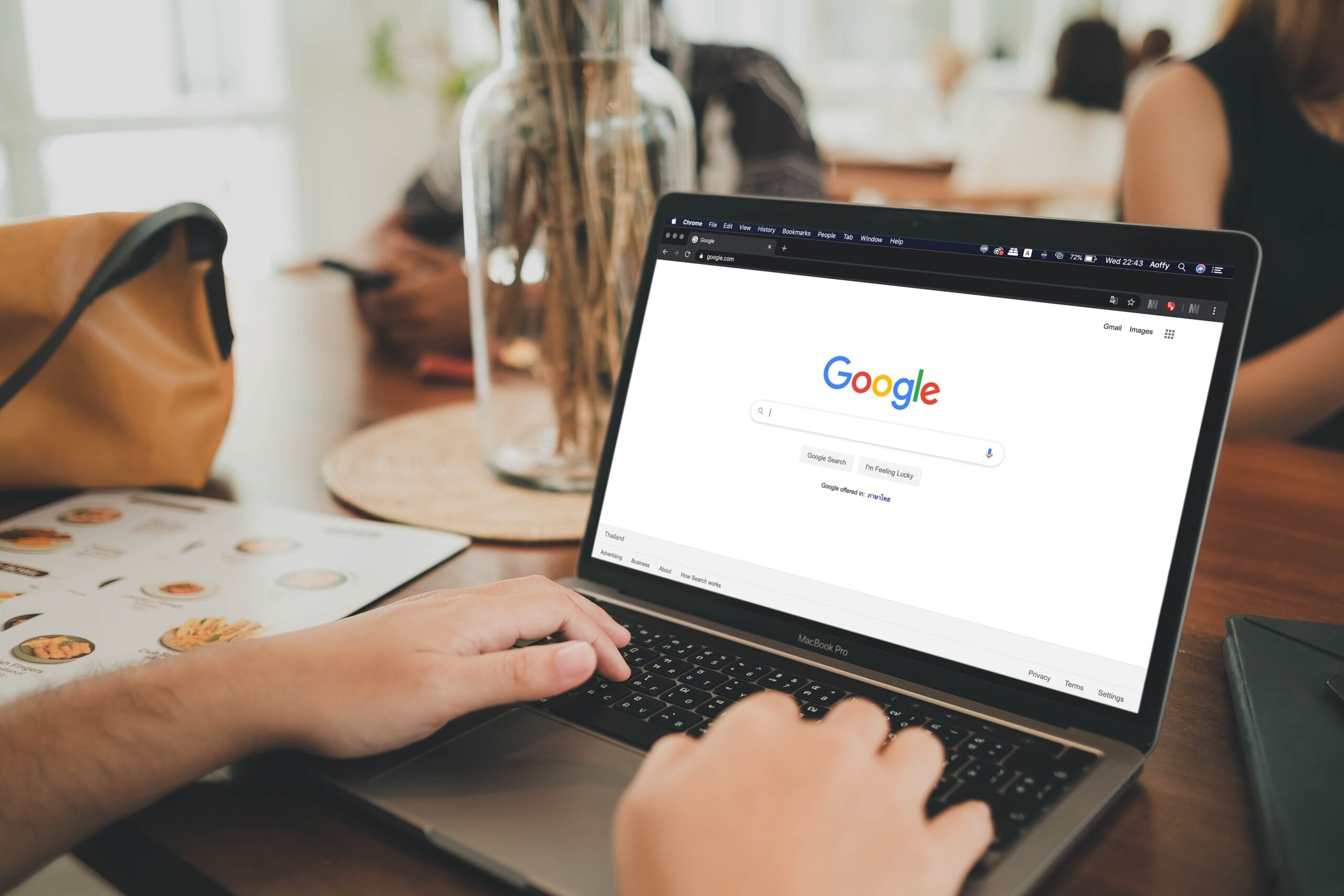 Person on laptop at a table looking at Google search homepage.